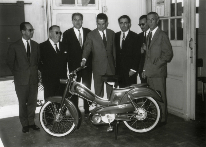 Groupe d'hommes autour de la cinquante-millième Motobécane vendue au Maroc : photographie noir et blanc.