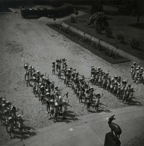 École de Plein-Air, enfants en rang en extérieur, face à la sculpture Petite antilope : photographie noir et blanc.