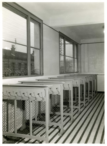 École maternelle de la route des Petits-Ponts, porte-manteaux à l'intérieur de l'établissement scolaire : photographie noir et blanc.