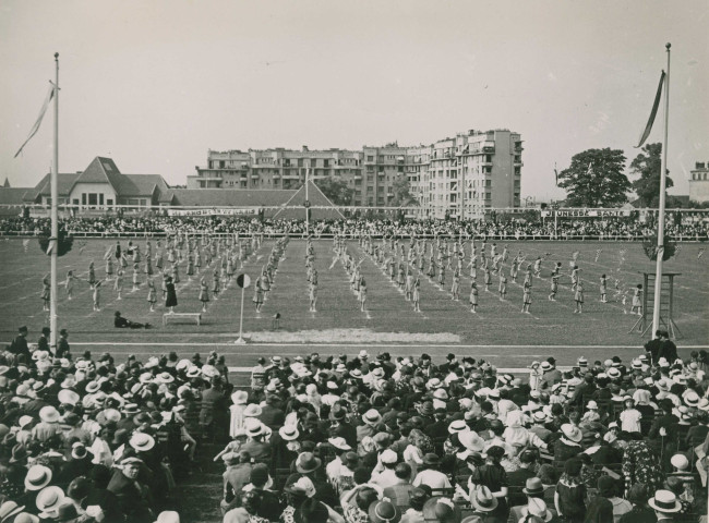 Fête d'éducation physique, vue large sur les mouvements d'ensemble, les spectateurs et les alentours au nord du stade : photographie noir et blanc.