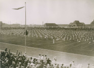 Fête d'éducation physique, vue large sur les mouvements d'ensemble, les spectateurs et les alentours au nord du stade : photographie noir et blanc.
