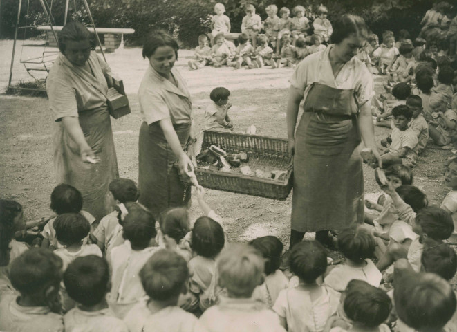 École de Plein-Air, distribution du goûter aux enfants assis en extérieur : photographie noir et blanc.