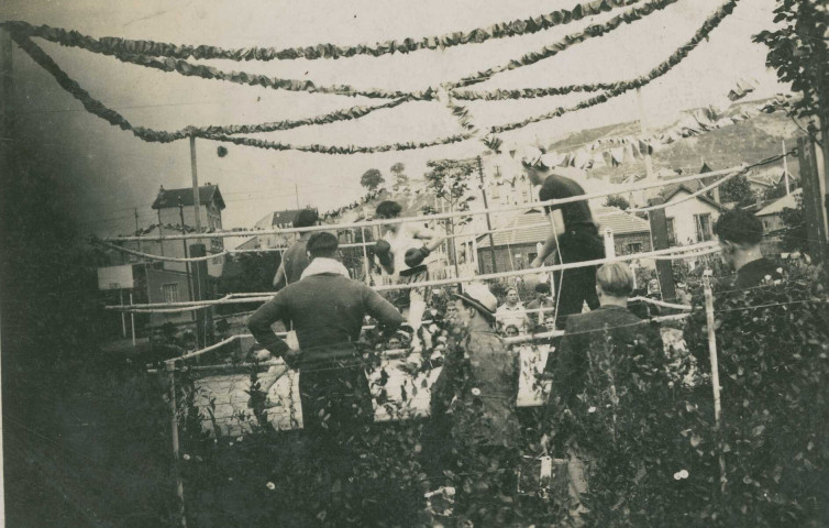 Combat de boxe sur un ring en extérieur : photographie noir et blanc.
