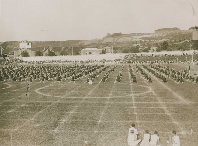 Fête d'éducation physique, vue large sur les mouvements d'ensemble, les spectateurs et les alentours à l'est du stade : photographie noir et blanc.
