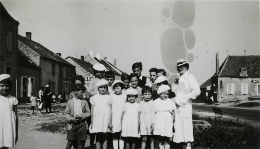 Colonies de vacances dans le nord du Morvan, groupe d'enfants posant avec l'épouse du maire Charles Auray à la Roche-en-Brenil : photographie noir et blanc.