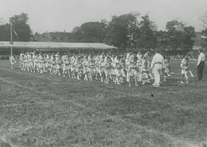 Fête d'éducation physique, défilé des enfants en portant d'autres sur leur dos : photographie noir et blanc.
