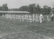 Fête d'éducation physique, défilé des enfants en portant d'autres sur leur dos : photographie noir et blanc.