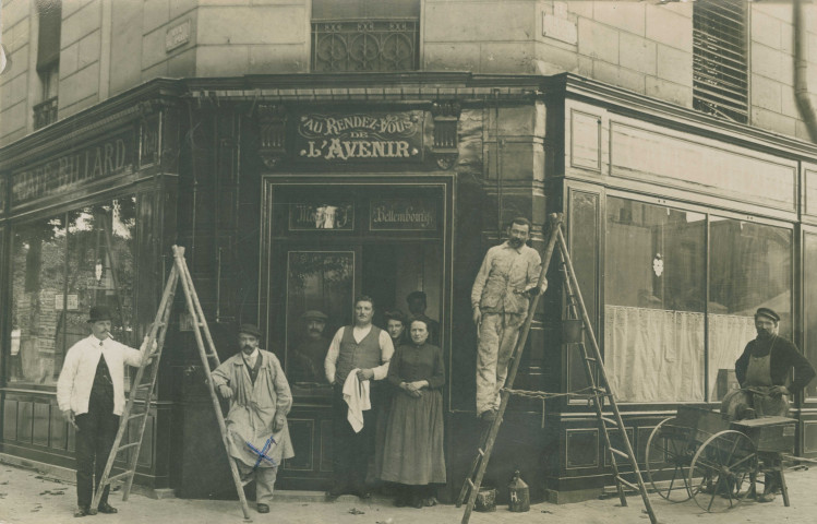 Photographie d'un groupe d'hommes posant devant le café-billard « Au rendez-vous de l'avenir » à l'angle des rues de Paris et de Palestro.
