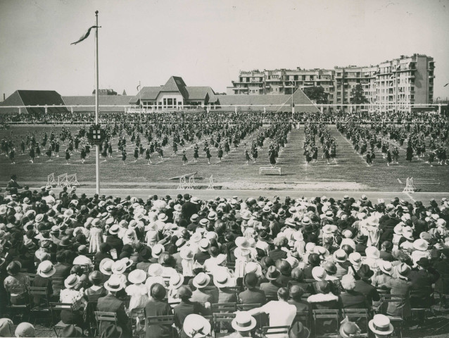 Fête d'éducation physique, vue large sur les mouvements d'ensemble, les spectateurs et les alentours au nord du stade : photographie noir et blanc.