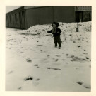 Portrait de Josiane Pillot devant un bâtiment de la cité d'urgence des Courtillières : photographie en noir et blanc.