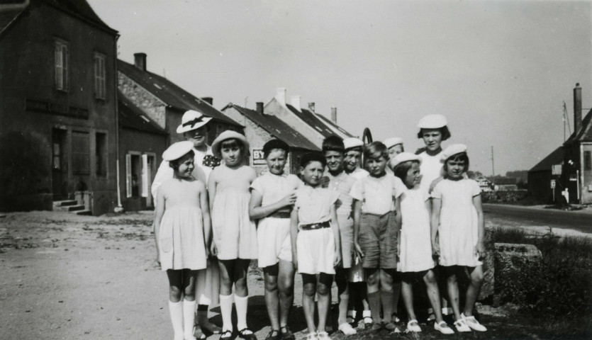 Colonies de vacances dans le nord du Morvan, groupe d'enfants posant avec l'épouse du maire Charles Auray : photographie noir et blanc.