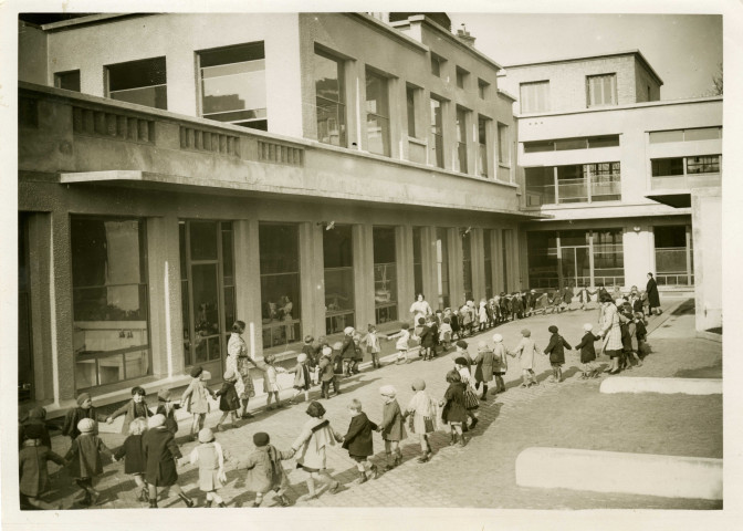 École maternelle de la route des Petits-Ponts, enfants faisant la ronde dans la cour : photographie noir et blanc.
