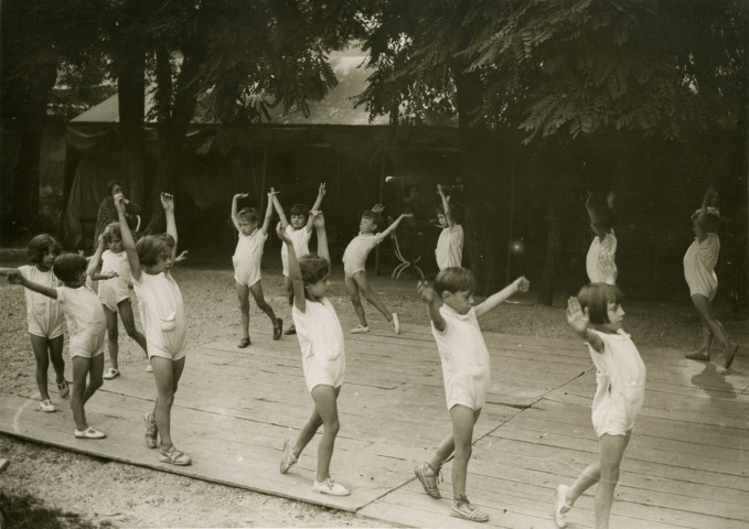 École de Plein-Air, enfants faisant de la gymnastique dehors : photographie en noir et blanc.
