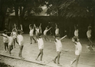École de Plein-Air, enfants faisant de la gymnastique dehors : photographie en noir et blanc.