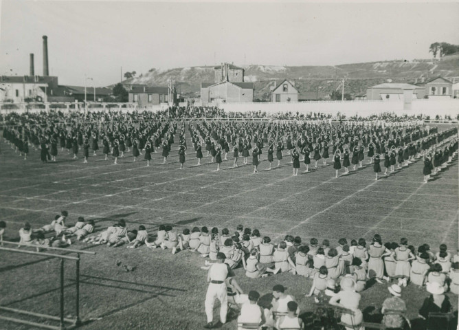 Fête d'éducation physique, vue large sur les mouvements d'ensemble, les spectateurs et les alentours à l'est du stade : photographie noir et blanc.