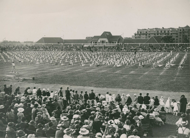 Fête d'éducation physique, vue large sur les mouvements d'ensemble, les spectateurs et les alentours au nord du stade : photographie noir et blanc.