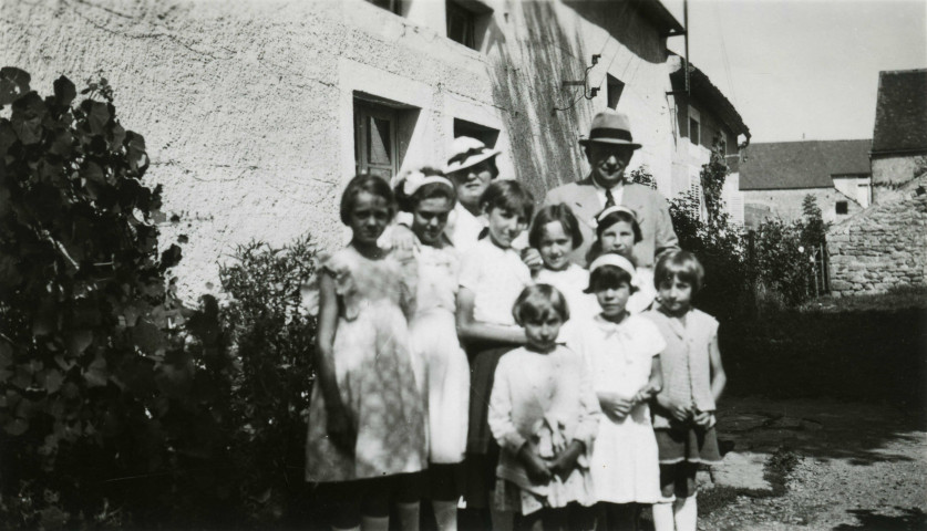 Colonies de vacances dans le nord du Morvan, groupe d'enfants posant avec le maire Charles Auray et son épouse au Frêne : photographie noir et blanc.