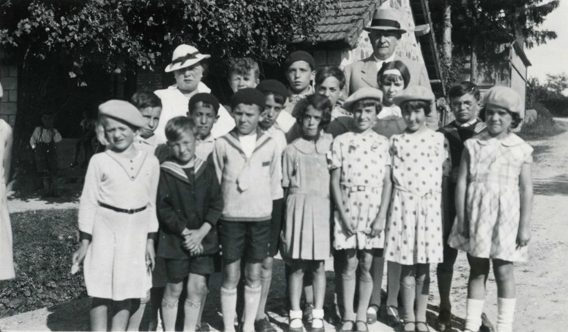 Colonies de vacances dans le nord du Morvan, groupe d'enfants posant avec le maire Charles Auray et son épouse à Bussières : photographie noir et blanc.