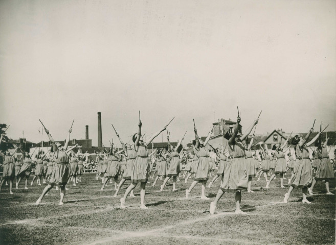 Fête d'éducation physique, mouvements d'ensemble avec des bâtons : photographie noir et blanc.