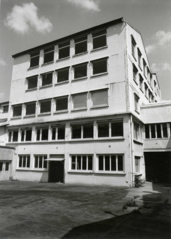 Usine Motobécane désaffectée, vue d'un bâtiment depuis la cour : photographie noir et blanc.
