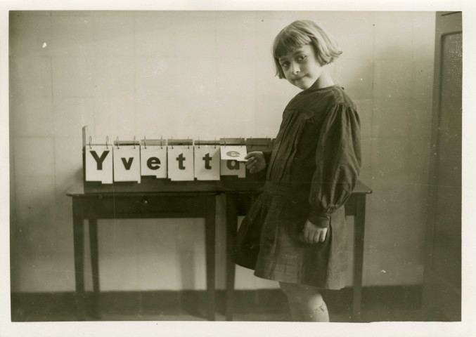 École maternelle de la route des Petits-Ponts, enfant apprenant à écrire son prénom : photographie noir et blanc.