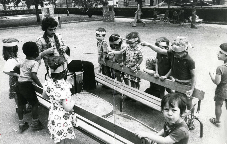 Enfants déguisés jouant avec des cannes à pêche dans un parc : photographie noir et blanc.