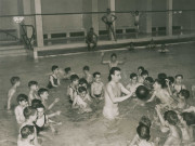 Piscine municipale, enfants jouant au ballon dans l'eau avec Jean Taris : photographie noir et blanc.