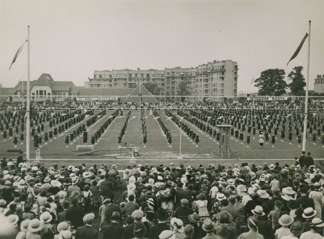 Fête d'éducation physique, vue large sur les mouvements d'ensemble, les spectateurs et les alentours au nord du stade : photographie noir et blanc.