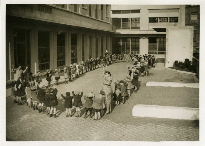 École maternelle de la route des Petits-Ponts, enfants faisant la ronde dans la cour : photographie noir et blanc.